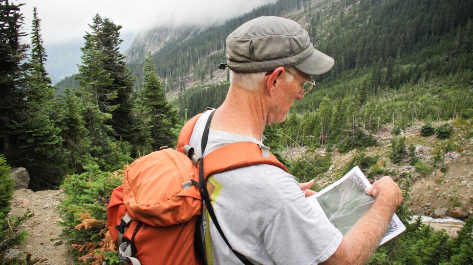caption: Dan Miller, a geomorphologist, hikes to a potential debris field in the North Cascades to look for signs in the landscape of landslides. 