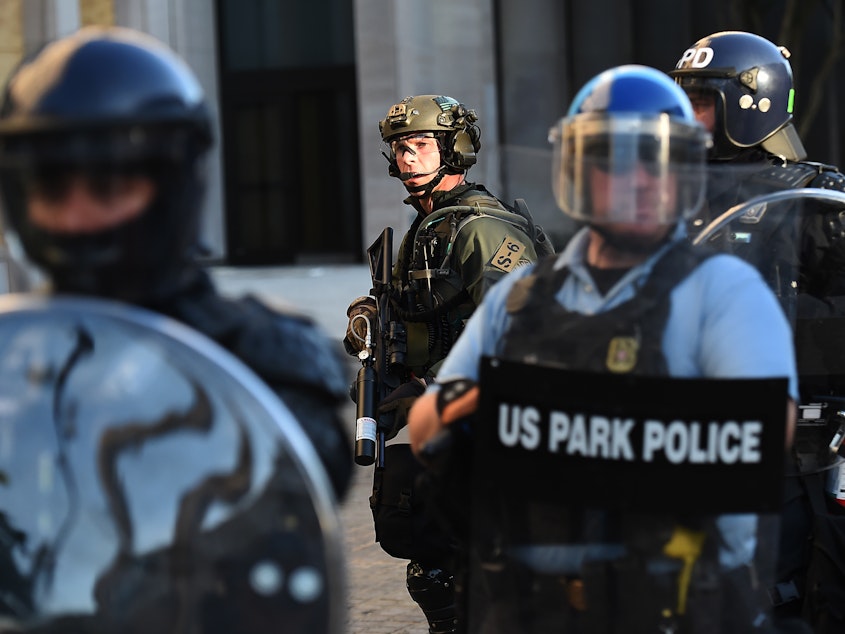caption: U.S. Park Police and other federal officers held a perimeter near the White House on June 1, 2020 as demonstrators gathered to protest the killing of George Floyd.