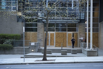 caption: A Seattle police officer exits the police department's boarded-up West precinct building following the reading of the guilty verdict in the trial of Derek Chauvin for the murder of George Floyd, on Tuesday, April 20, 2021, along Virginia Street in Seattle.