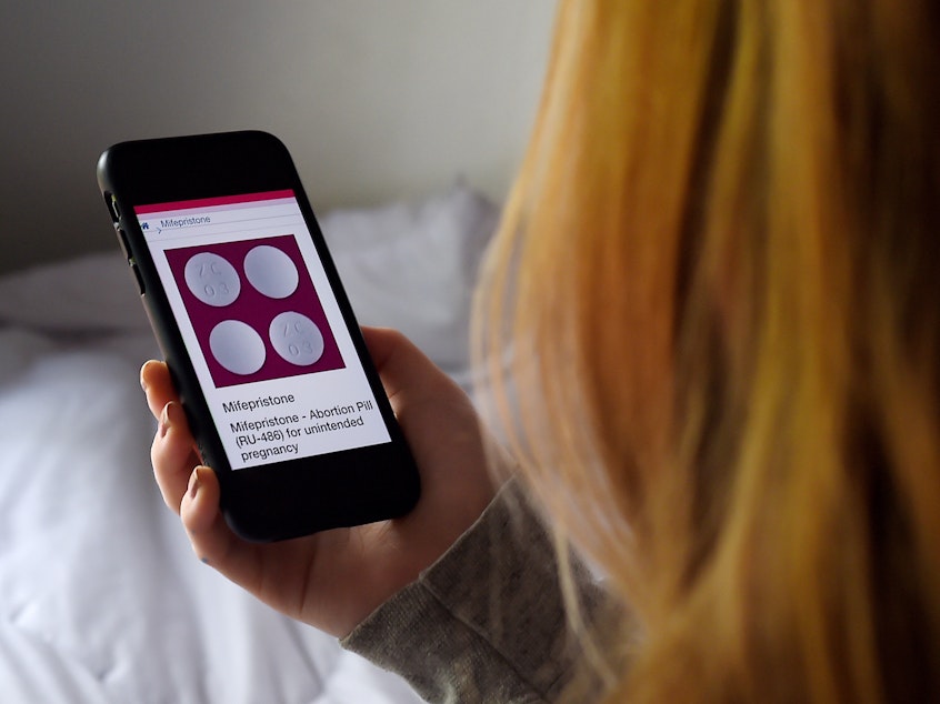 In this photo illustration, a person looks at the drug mifepristone on their smartphone.