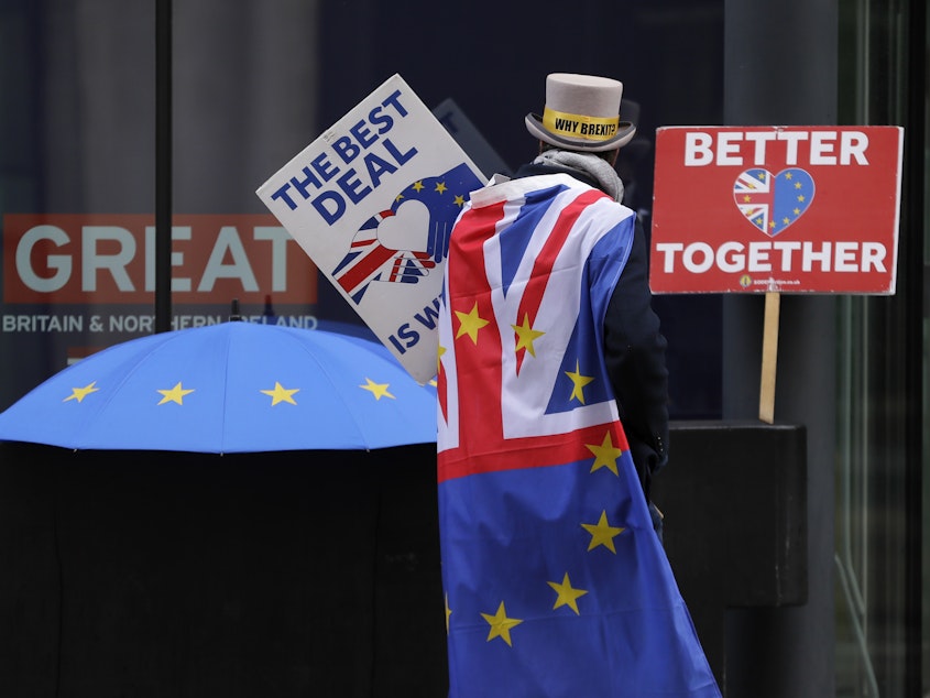 caption: A pro-EU demonstrator sets up banners outside a London conference center, where trade talks were being held on Dec. 4.