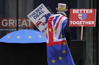 caption: A pro-EU demonstrator sets up banners outside a London conference center, where trade talks were being held on Dec. 4.