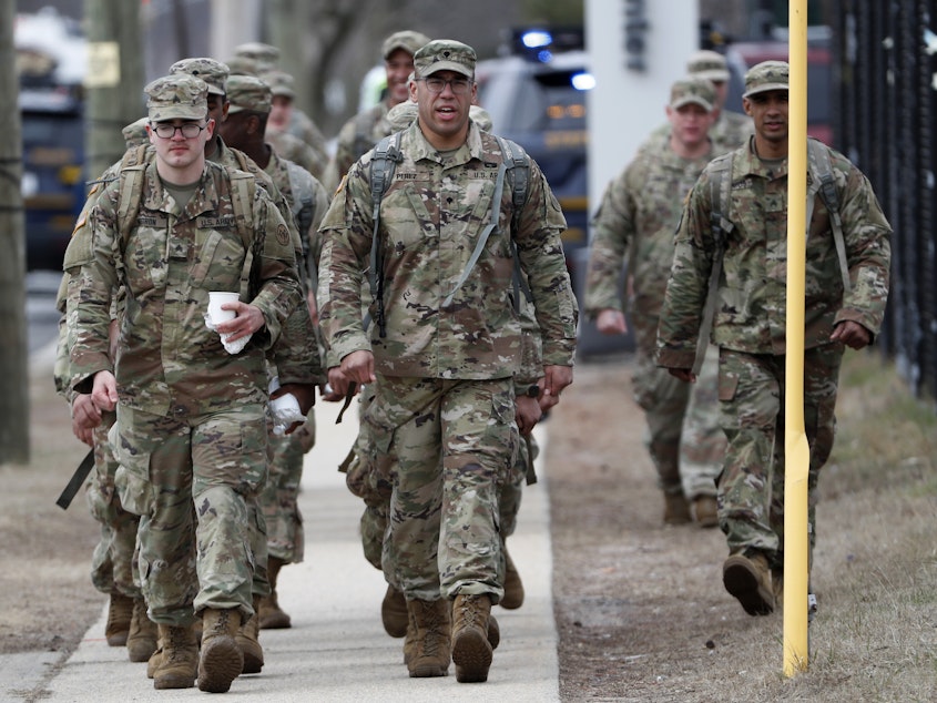 caption: National Guard personnel march in formation Thursday at a state-managed coronavirus drive-through testing site that just opened on Staten Island in New York.