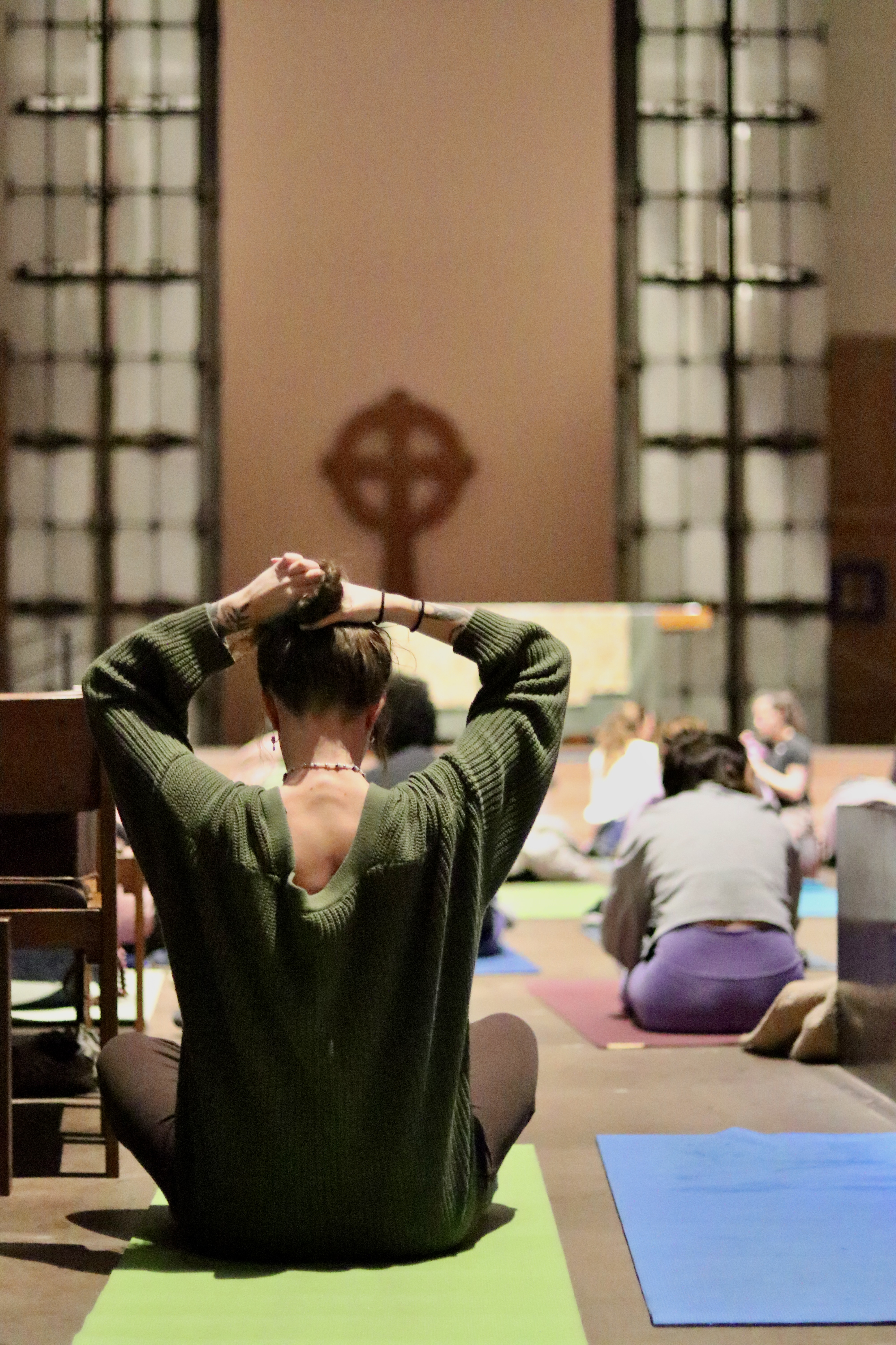 caption: One yoga goer ties up their hair to prepare for the class. 