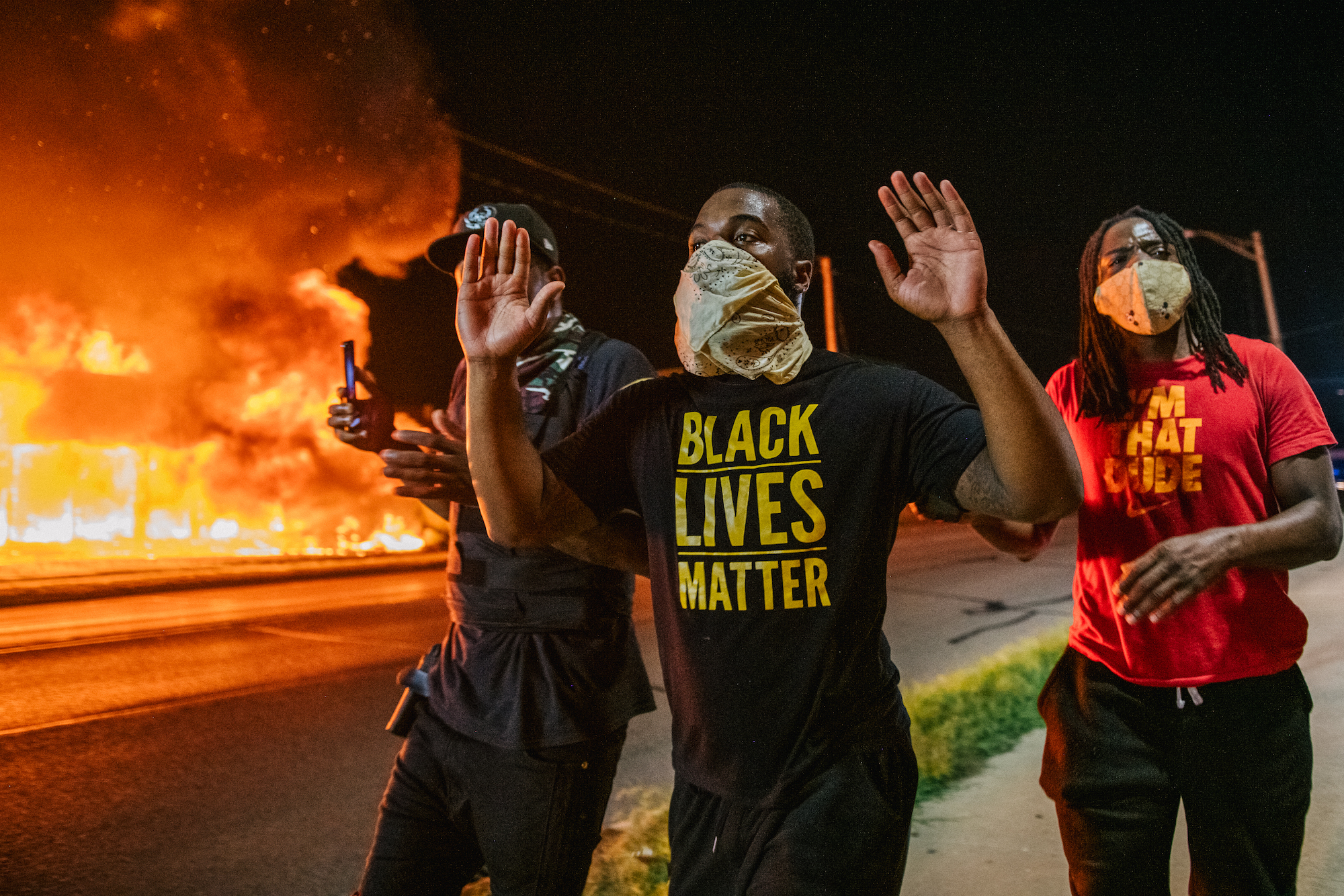 caption: Men walk towards law enforcement with their hands up on August 24, 2020 in Kenosha, Wisconsin. (Photo by Brandon Bell/Getty Images)