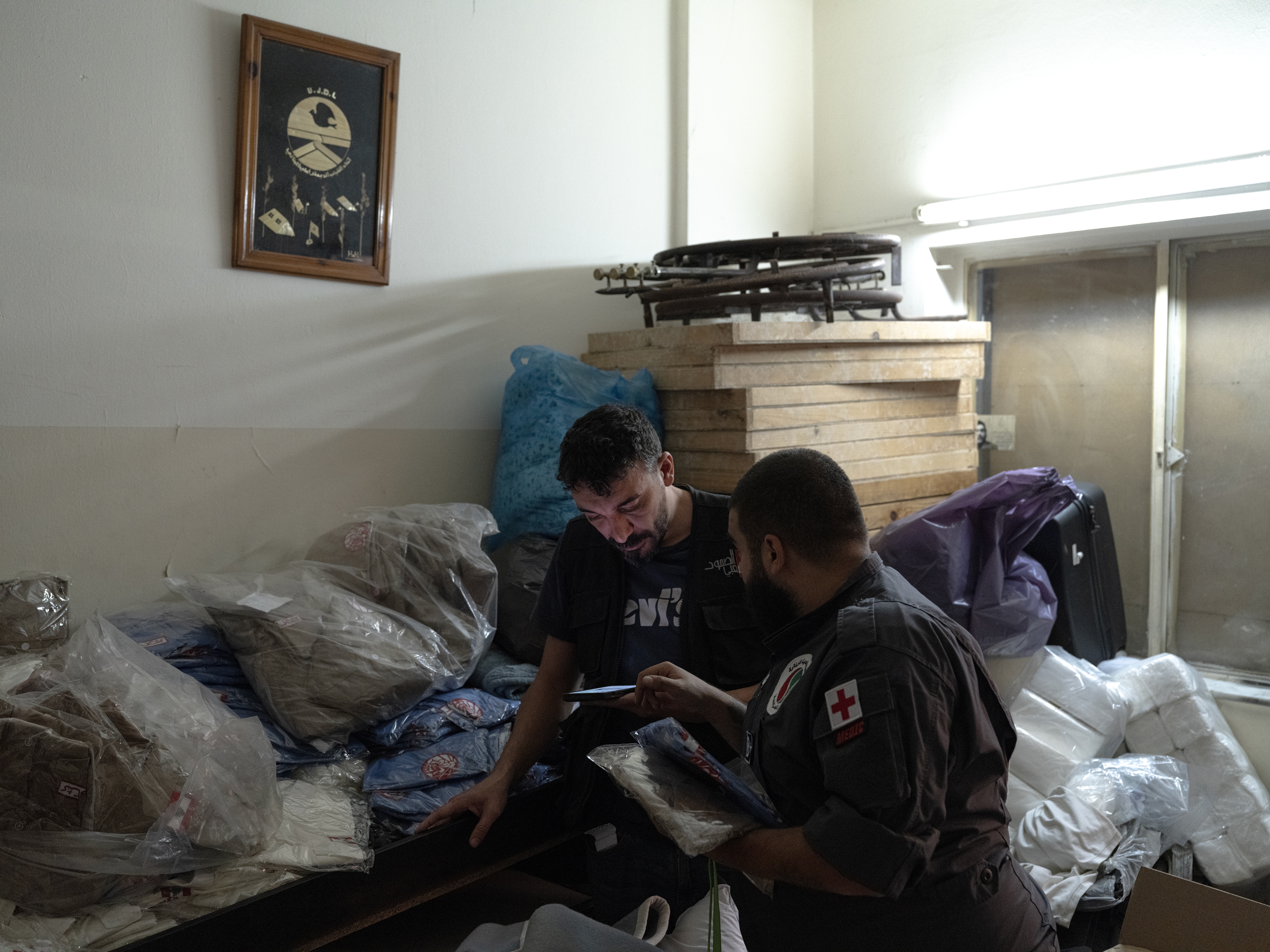 caption: Jad Deeb, a volunteer of the Lebanese Popular Relief Association, prepares school clothes for displaced Lebanese children with one of his colleagues in their office in Beirut, Lebanon.