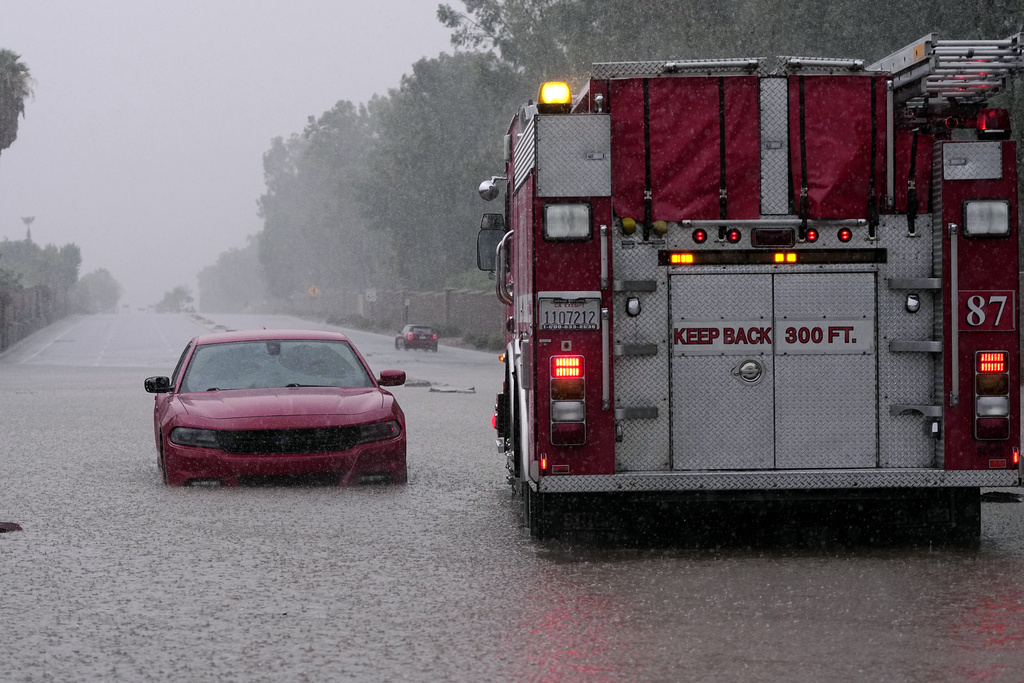 caption: A fire truck pulls away after a motorist became stranded in rising floodwaters caused by torrential rain brought by Tropical Storm Hilary, Sunday, Aug. 20, 2023, in Palm Desert, Calif. 