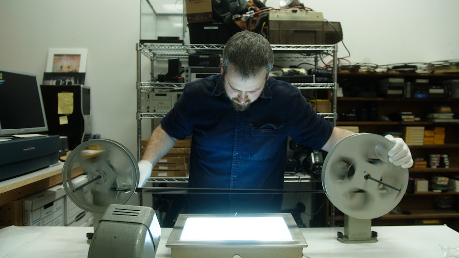 caption: Director Isaac Olsen views archived 35mm film using a light box. 