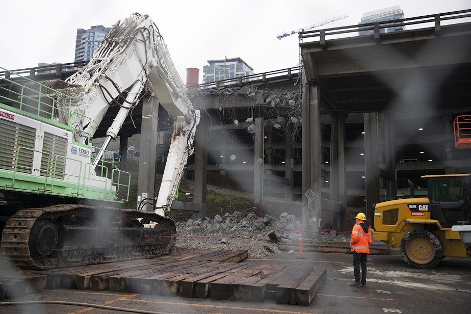 caption: A portion of the Alaskan Way Viaduct is demolished on Monday, February 18, 2019, seen from the intersection of Pine and Alaskan Way in Seattle. 1.4 miles of the roadway, weighing roughly 122,000 tons, will be demolished. 