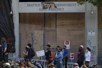 caption: A crowd gathers at the intersection of 12th Avenue and East Pine Street, outside of the Seattle Police Department's East Precinct building, in the 'Capitol Hill Autonomous Zone', also known as CHAZ, on Wednesday, June 10, 2020, in Seattle.