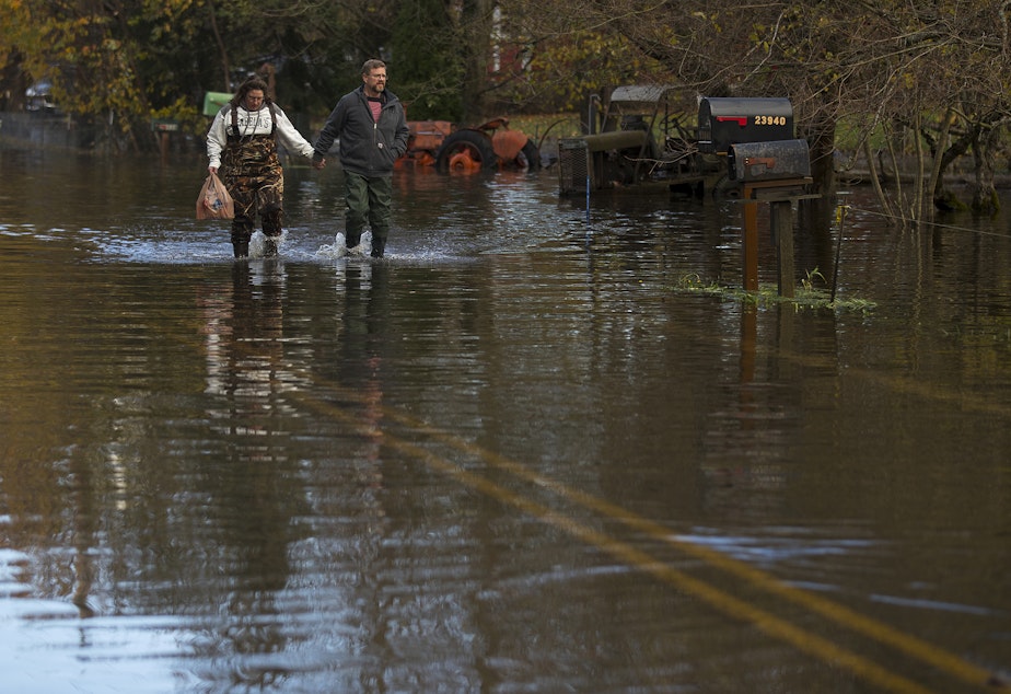 caption: Robby and Sara Burt walk through a flooded stretch of Old Day Creek Road toward Robby's mother's home, on Tuesday, November 16, 2021, in Clear Lake. 