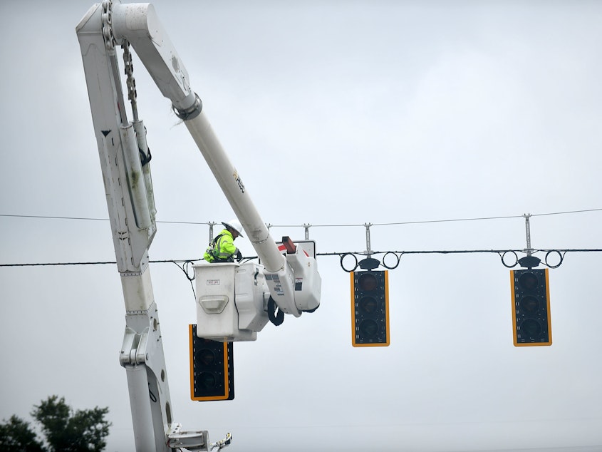 caption: A worker repairs traffic lights during a power outage following Hurricane Ian on Thursday in Bartow, Fla.
