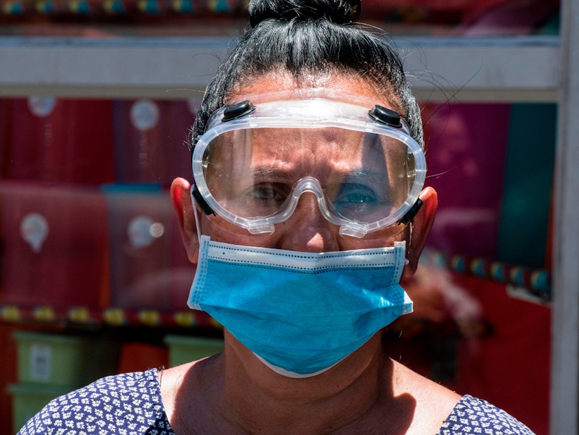 caption: A woman wears a face mask and goggles as a preventive measure against the new coronavirus.