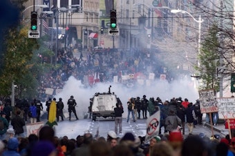caption: Seattle police use gas to push back World Trade Organization protesters in downtown Seattle Tuesday, Nov. 30, 1999. The protests delayed the opening of the WTO third ministerial conference. 