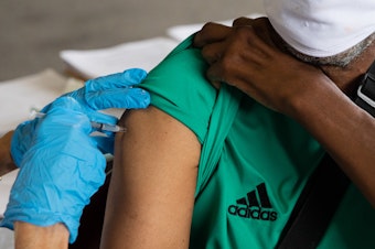 caption: Rufus Peoples receives a dose of the Pfizer-BioNTechCOVID-19 vaccine at an Oakland County Health Department vaccination clinic in Southfield, Mich., in August.