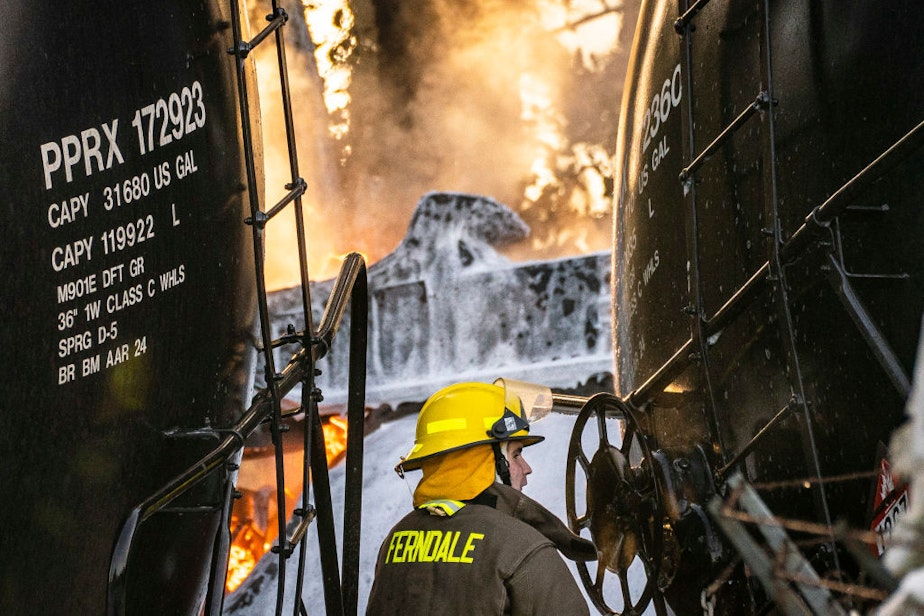caption: A firefighter works as a derailed train carrying crude oil burns on Dec. 22 in Custer, Washington. 