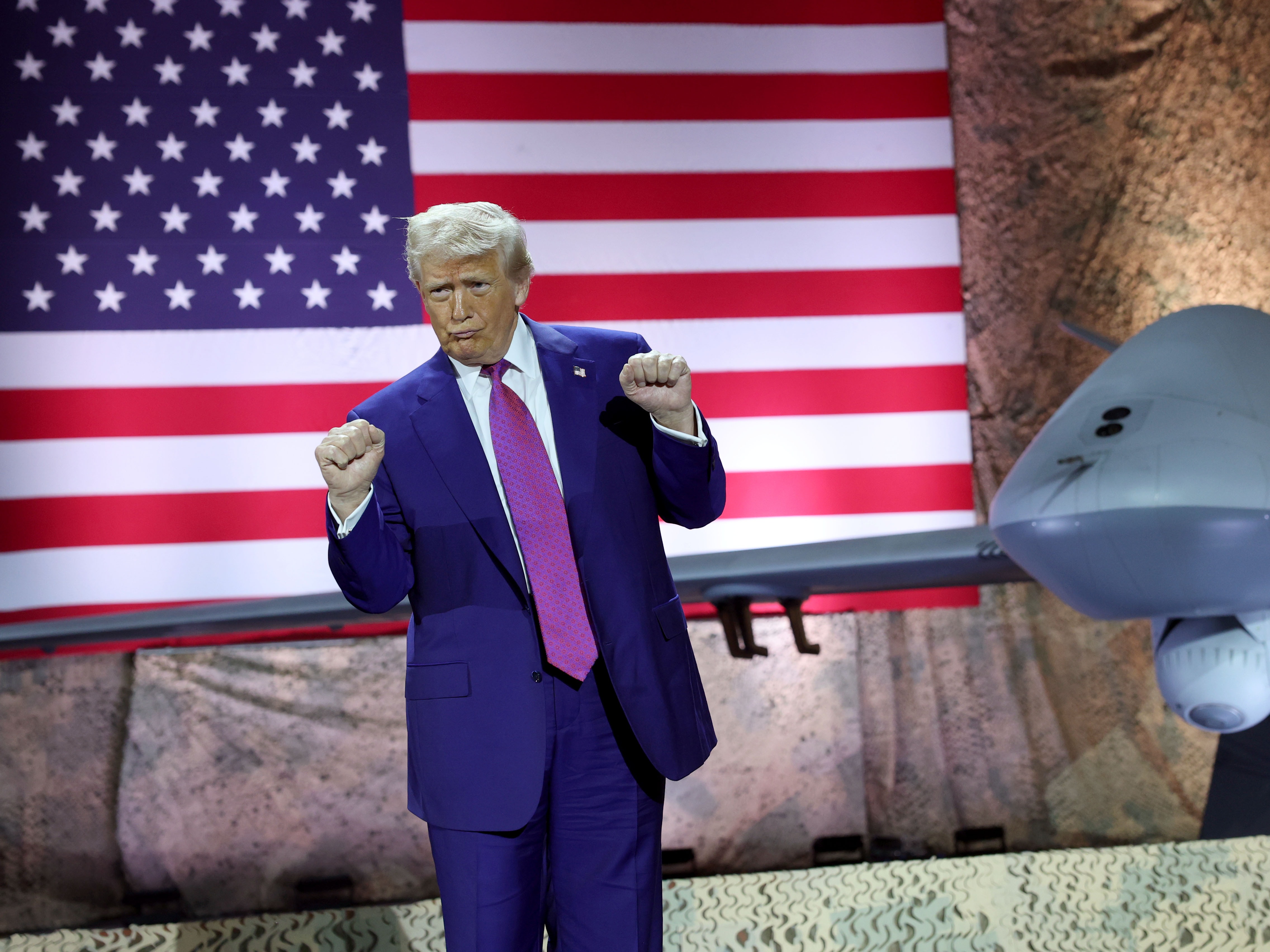 caption: President Trump dances as his campaign song "God Bless the U.S.A." plays on stage at the Al Udeid Air Base in Qatar on May 15, 2025.