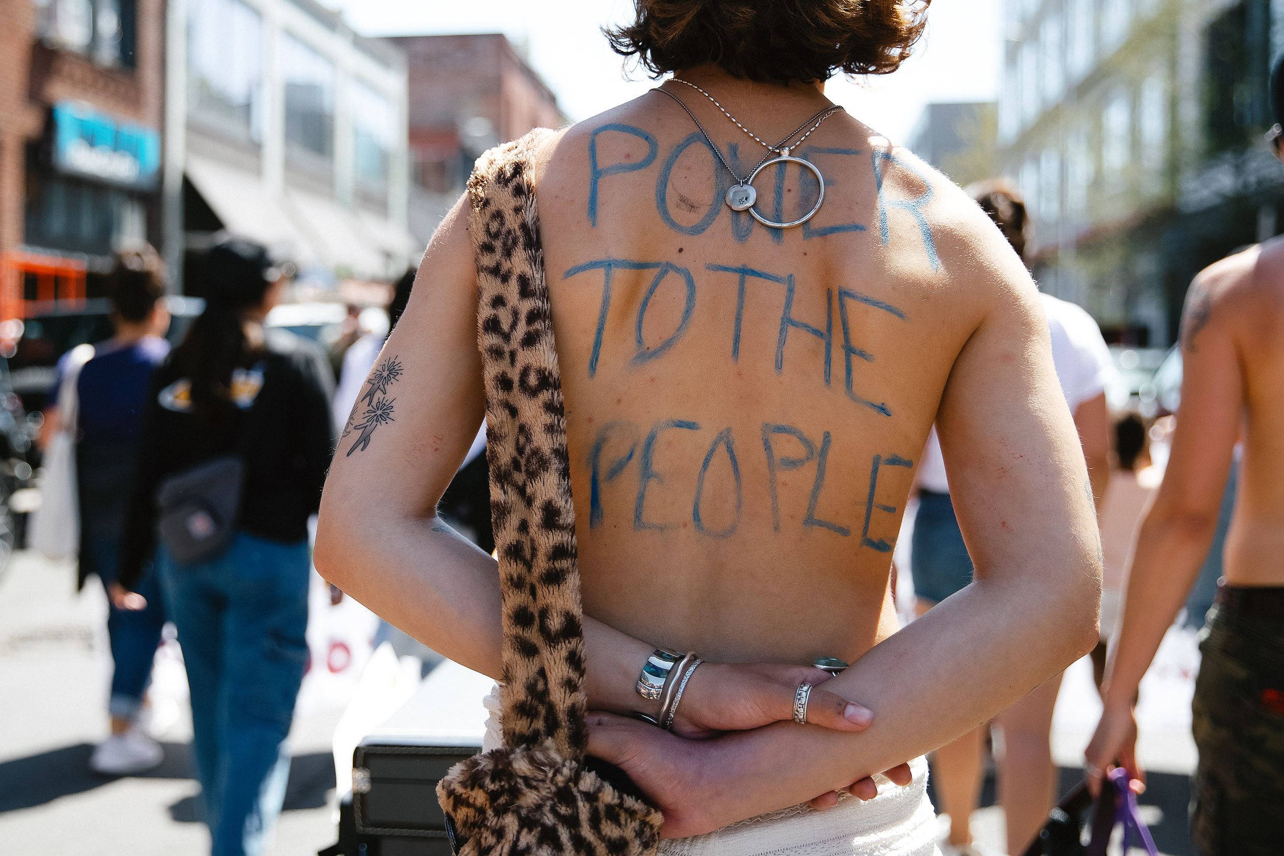 caption: 'Power To The People' is written on the back of a demonstrator during the annual May Day rally and march on Thursday, May 1, 2025, near Cal Anderson Park in Seattle. Activists say this year’s rally and march are primarily a response to the Trump administration's crackdown on immigrants and pro-labor groups.