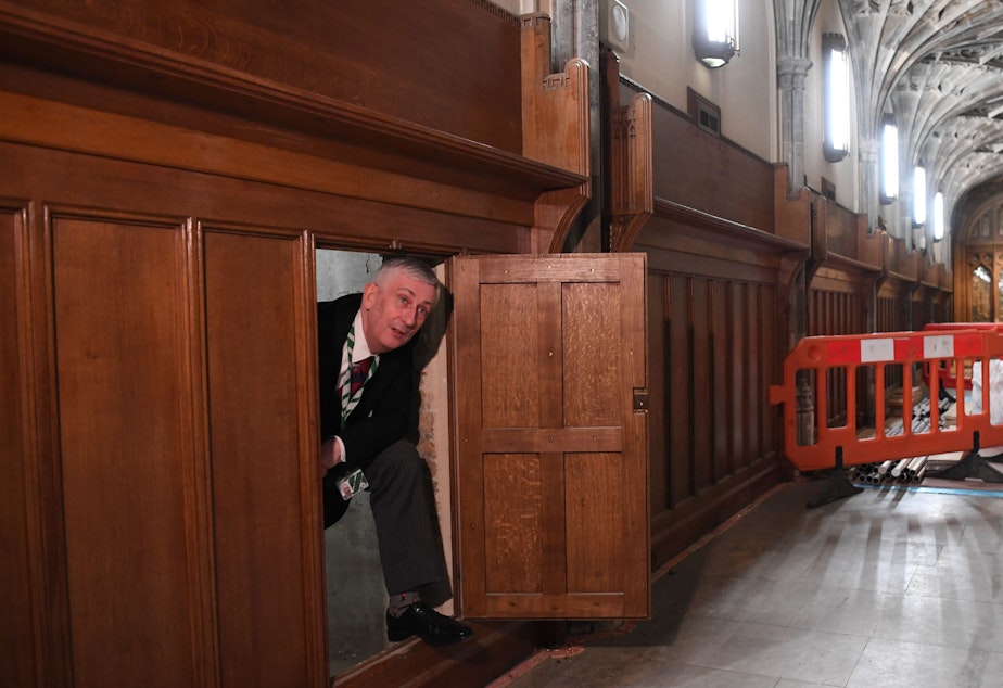 caption: Speaker of the U.K. House of Commons Lindsay Hoyle emerges from a chamber concealing a 360-year-old passageway that was rediscovered during renovation work in the Houses of Parliament in London.