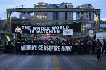 caption: Demonstrators calling for a permanent ceasefire in Gaza blocked four lanes of traffic Thursday, December 14, 2023, on Seattle's University Bridge. 