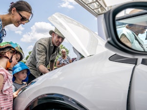 caption: A family inspects the engine of a new Toyota Prius model during the Electrify Expo In D.C. in Washington, D.C., on July 23, 2023. Getting an electric vehicle tax credit of up to $7,500 will get a lot easier next year.