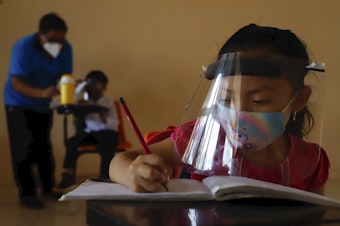 caption: Wearing a mask and a face shield to curb the spread of the coronavirus, 10-year-old Jade Chan Puc writes in her workbook during the first day of class in Hecelchakán, Campeche state, Mexico, on April 19. On average, schools in Latin America and the Caribbean were closed longer than any in any other region, according to UNICEF.