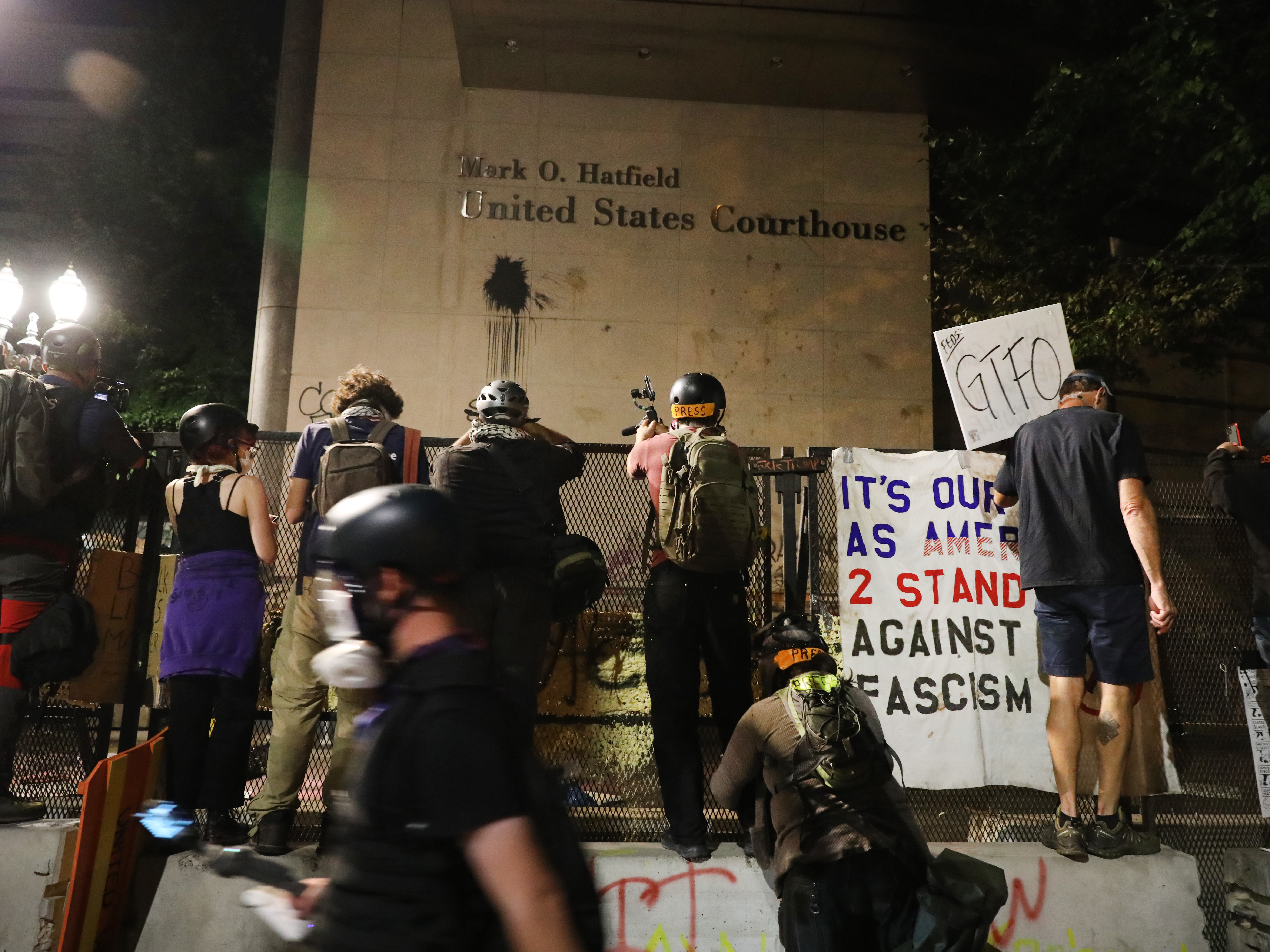 caption: Protesters gather in front of the Mark O. Hatfield federal courthouse in downtown Portland, where some demonstrators have been arrested and others released from jail on the condition that they not attend any more protests.