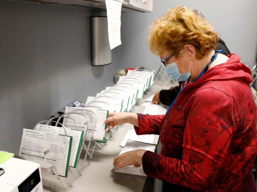 caption: An employee of the West Bloomfield Township Clerks office sorts absentee ballots by the precinct and ballot number at the West Bloomfield Clerks office on October 31, 2020 in West Bloomfield, Mich.