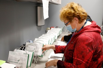 caption: An employee of the West Bloomfield Township Clerks office sorts absentee ballots by the precinct and ballot number at the West Bloomfield Clerks office on October 31, 2020 in West Bloomfield, Mich.