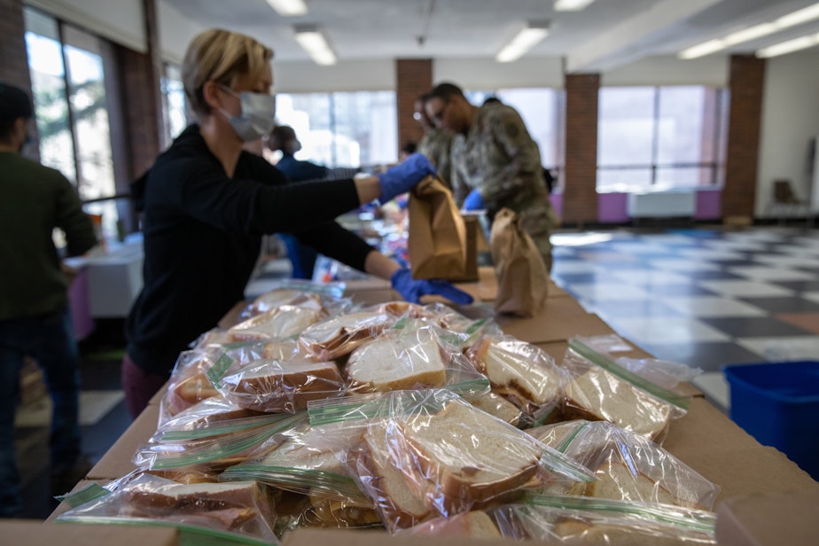 caption: Volunteer Rhiannon Navin and U.S. National Guard troops put together meals for distribution to local residents at the WestCop community center on March 18, 2020 in New Rochelle, New York. New Rochelle has been a hot spot for the COVID-19 pandemic in the U.S. (John Moore/Getty Images)
