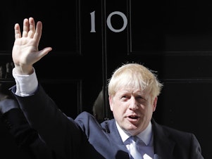 caption: Britain's new prime minister, Boris Johnson, waves from the steps outside 10 Downing Street in London on Wednesday.