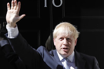 caption: Britain's new prime minister, Boris Johnson, waves from the steps outside 10 Downing Street in London on Wednesday.