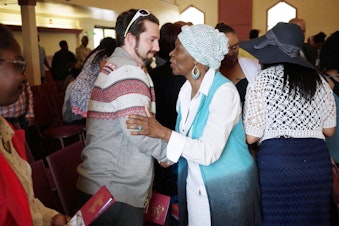 caption: Mount Calvary member Vera Brooks greets a newcomer at Sunday service.