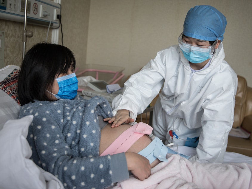 caption: A nurse examines a pregnant woman in a private obstetric hospital in Wuhan, Hubei Province, China, in February. Research from China suggests pregnancy does make women more vulnerable to the coronavirus.