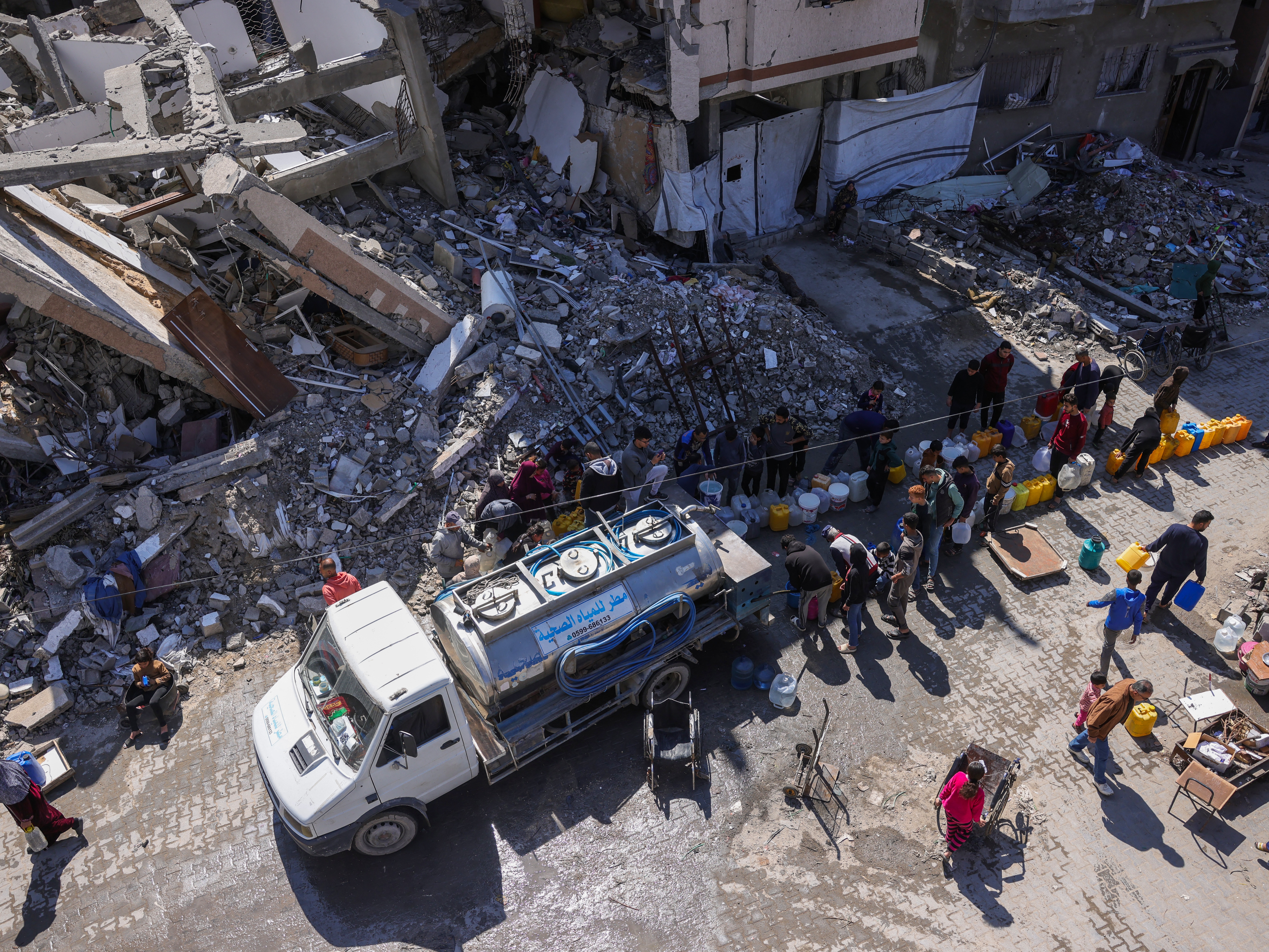 caption: Palestinians line up for water next to a distribution truck at a displacement camp in the northern Gaza Strip on Tuesday. Saudi Arabia, Qatar and Jordan condemned Israel's decision to cut electricity supply to the war-battered Gaza Strip, calling in separate statements for the international community to take action.