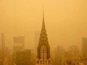 caption: Smoke from wildfires turned the skies orange behind New York's Chrysler Building in June 2023. The smoke affected millions across the central and eastern U.S.