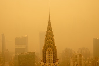 caption: Smoke from wildfires turned the skies orange behind New York's Chrysler Building in June 2023. The smoke affected millions across the central and eastern U.S.