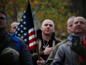 caption: Attendees recite the Pledge of Allegiance during the "United Against Hate" rally by the Washington Three Percent in Seattle last month.