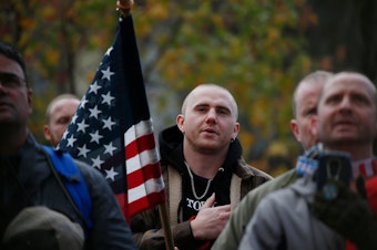 caption: Attendees recite the Pledge of Allegiance during the "United Against Hate" rally by the Washington Three Percent in Seattle last month.