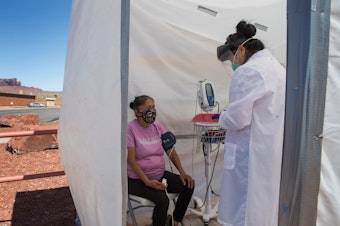 caption: A nurse checks vitals for a Navajo woman, who came to a coronavirus testing center in Arizona, complaining of virus symptoms.
