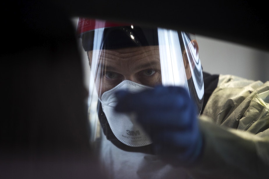 caption: Brodie Smith, a Captain with Vashon Island Fire & Rescue, administers a Covid-19 test on Wednesday, November 18, 2020, in the parking lot of the Weyerhaeuser King County Aquatic Center along Southwest Campus Drive in Federal Way. 