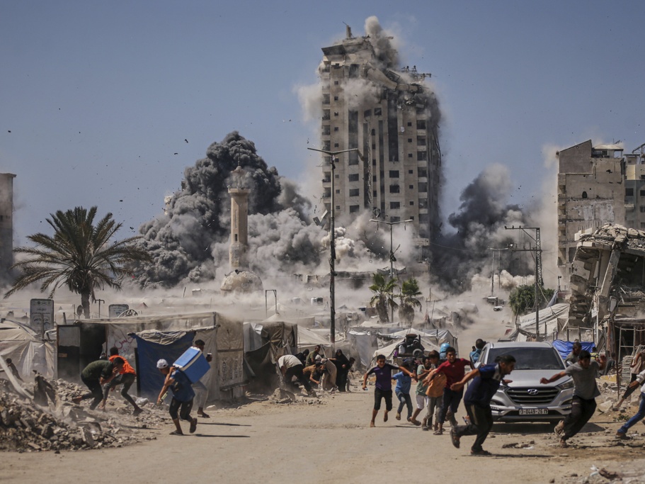 caption: Palestinians run for cover during a Sept. 5 Israeli airstrike on a high-rise building in Gaza City after the Israeli army issued a warning.
