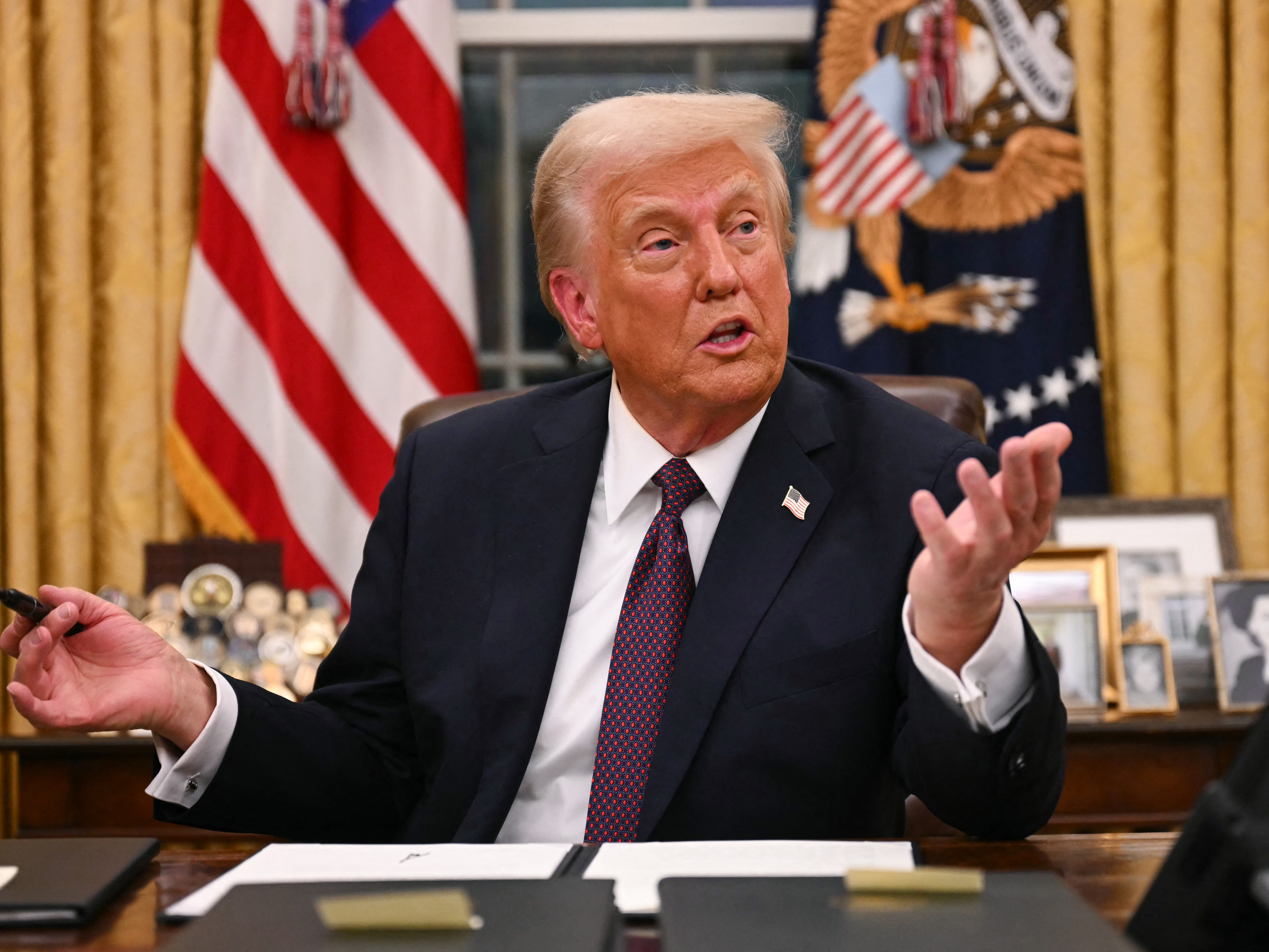 caption: President Trump speaks to journalists as he signs an executive order regarding Department of Government Efficiency (DOGE), in the Oval Office of the White House on Jan. 20.