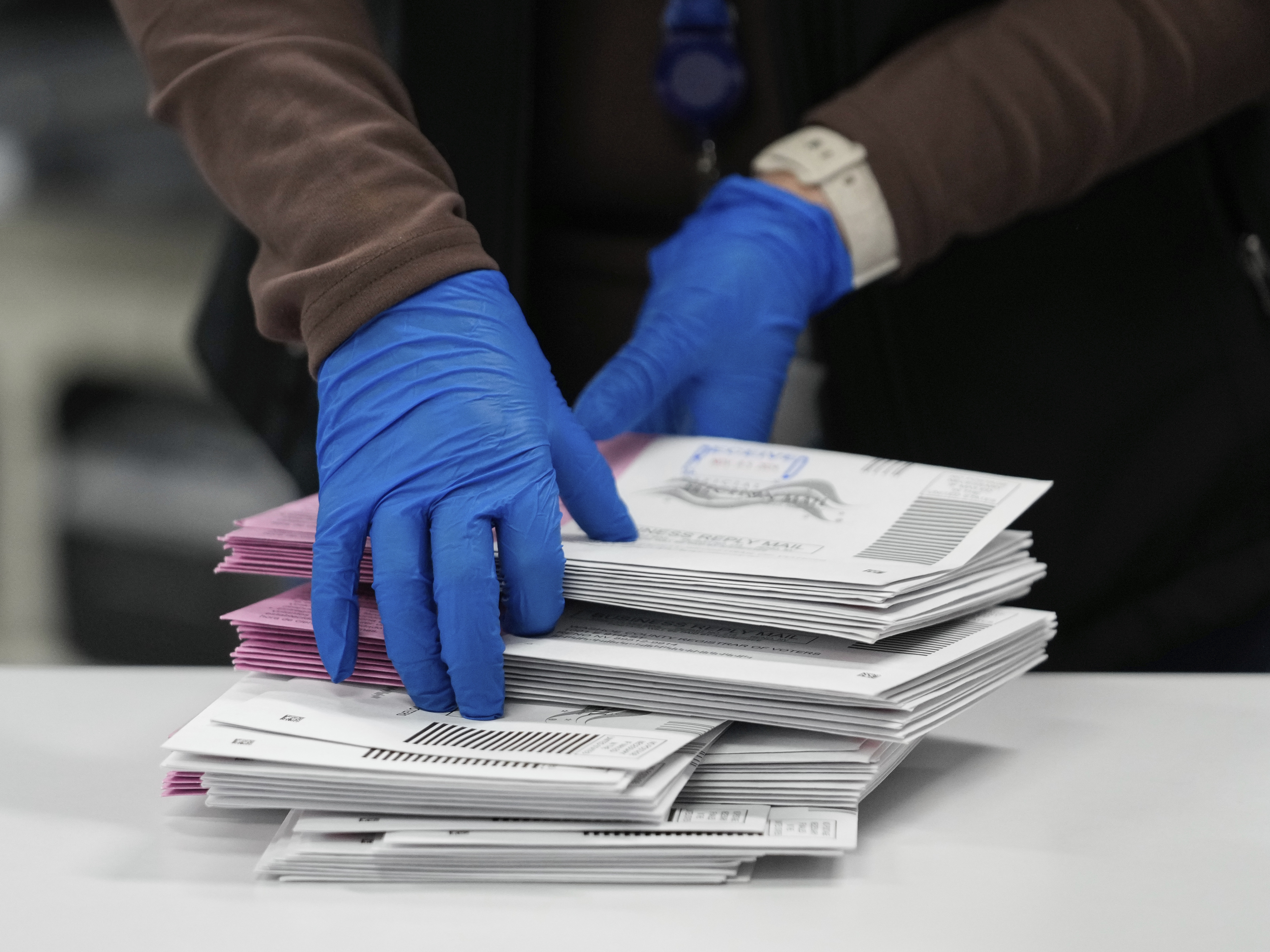 caption: An election worker sorts mail-in ballots in Reno, Nev., on Nov. 5, 2024.