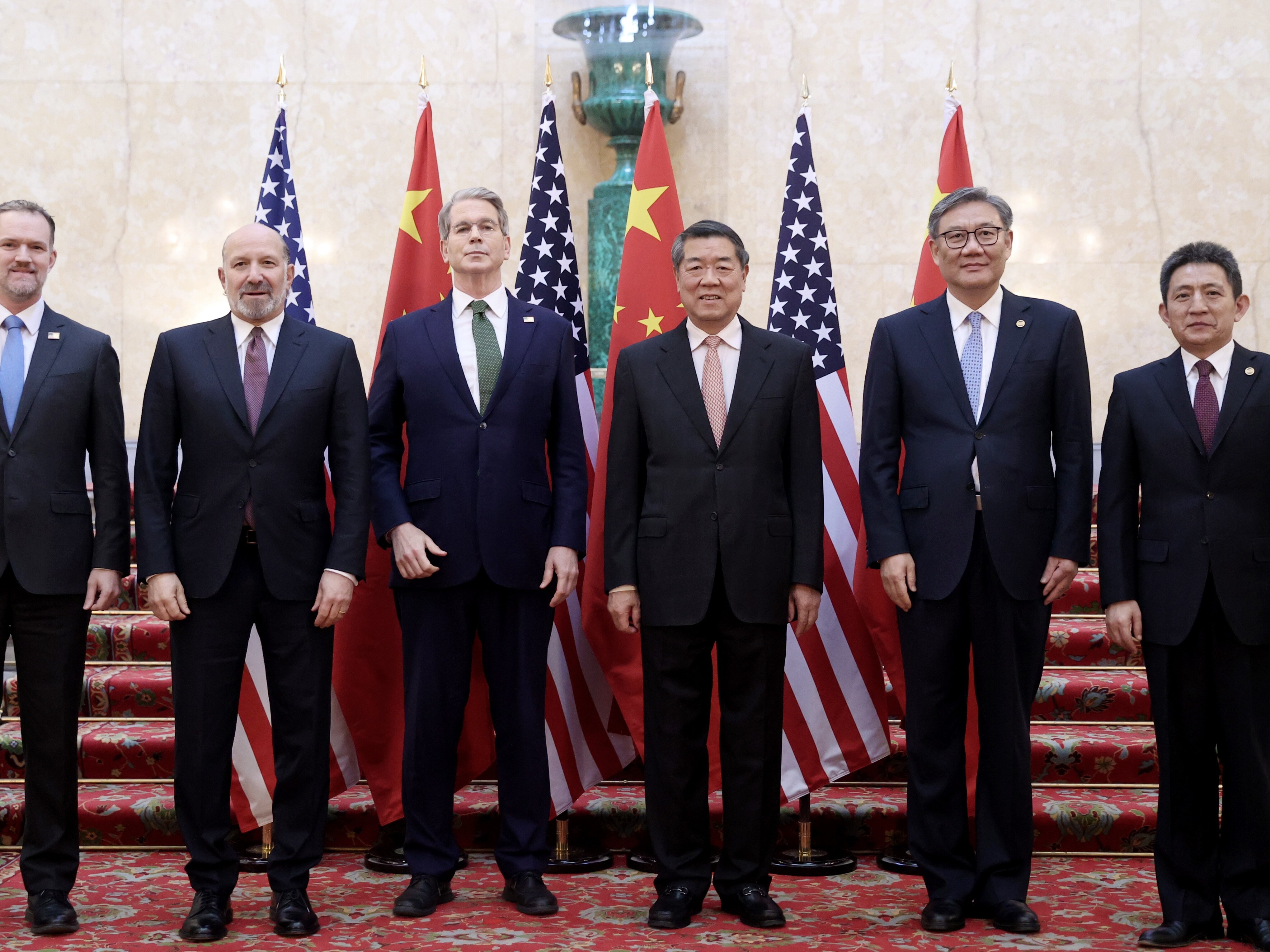 caption: Chinese Vice Premier He Lifeng, center right, and U.S. Treasury Secretary Scott Bessent, center left,  with their delegations before their meeting to discuss U.S.-China trade in London on Monday. Talks are continuing Tuesday.