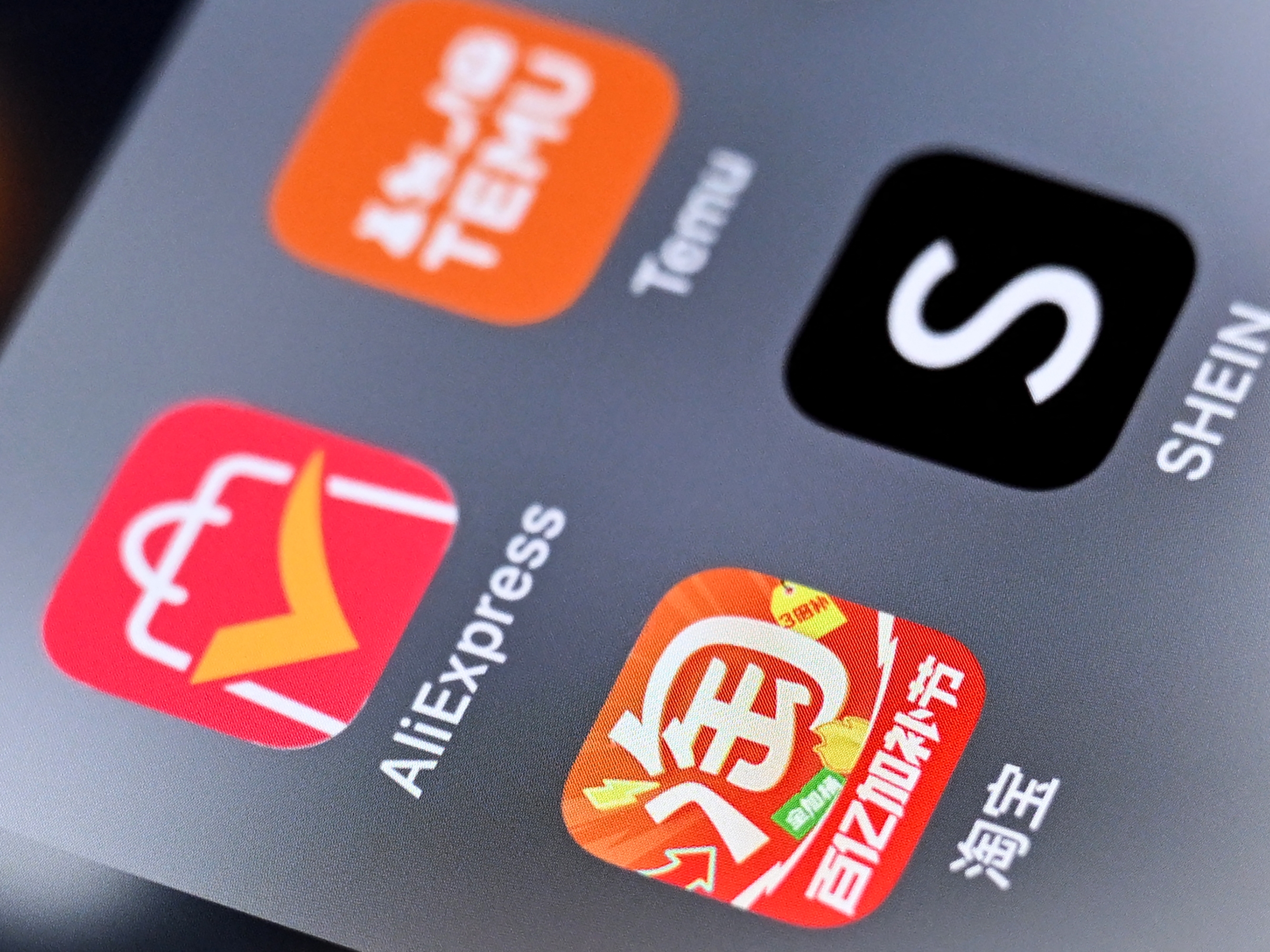 caption: An illustration photo of the logos of Chinese shopping apps Taobao, AliExpress (L), Shein (R) and Temu on a smartphone screen.