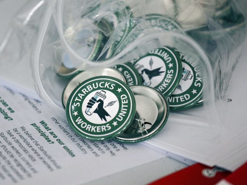 caption: Pro-union pins sit on a table during a watch party for Starbucks' employees union election, Dec. 9, 2021, in Buffalo, N.Y. The top lawyer for the National Labor Relations Board said Thursday, April 7, she will ask the board to rule that mandatory meetings some companies hold to persuade their workers reject unions is in violation of federal labor law.