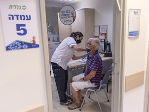 caption: The director of WHO now says that a booster moratorium should be in force until 10% of the population in all countries is vaccinated. Israel had previously announced plans to give a third Pfizer dose to residents age 60 and up after an uptick in COVID cases. Above: Administering a booster on August 2 in Tel Aviv.