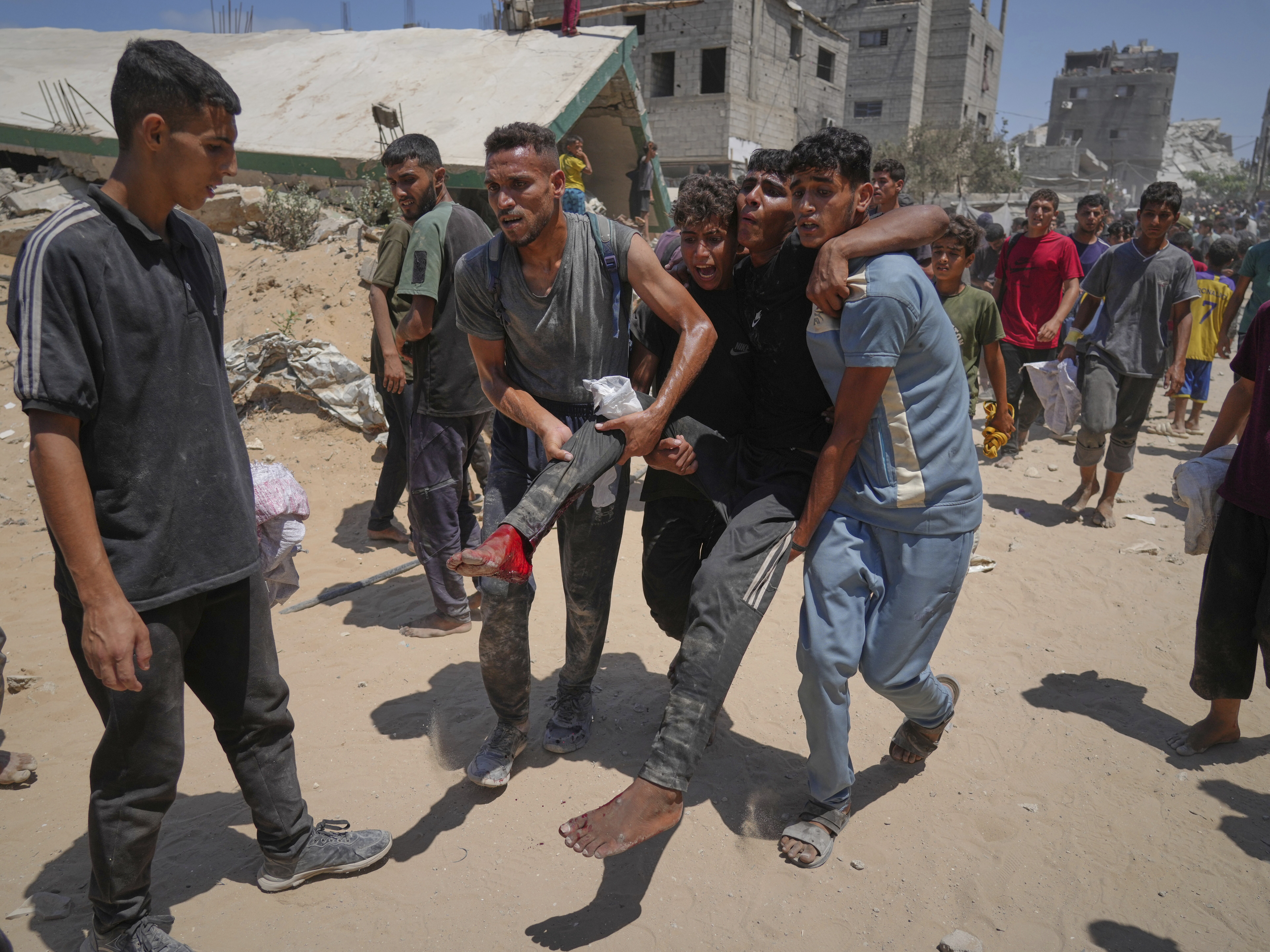 caption: Palestinians carry a wounded man who was injured while rushing to collect humanitarian aid airdropped by parachute into Gaza City, in the northern Gaza Strip, on Aug. 7.