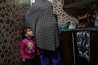 caption: Sally Zeita, 3, stands beside her mother Amani as she prepares a Ramadan dessert at their home in the village Ein 'Arik in the occupied West Bank on March 24.